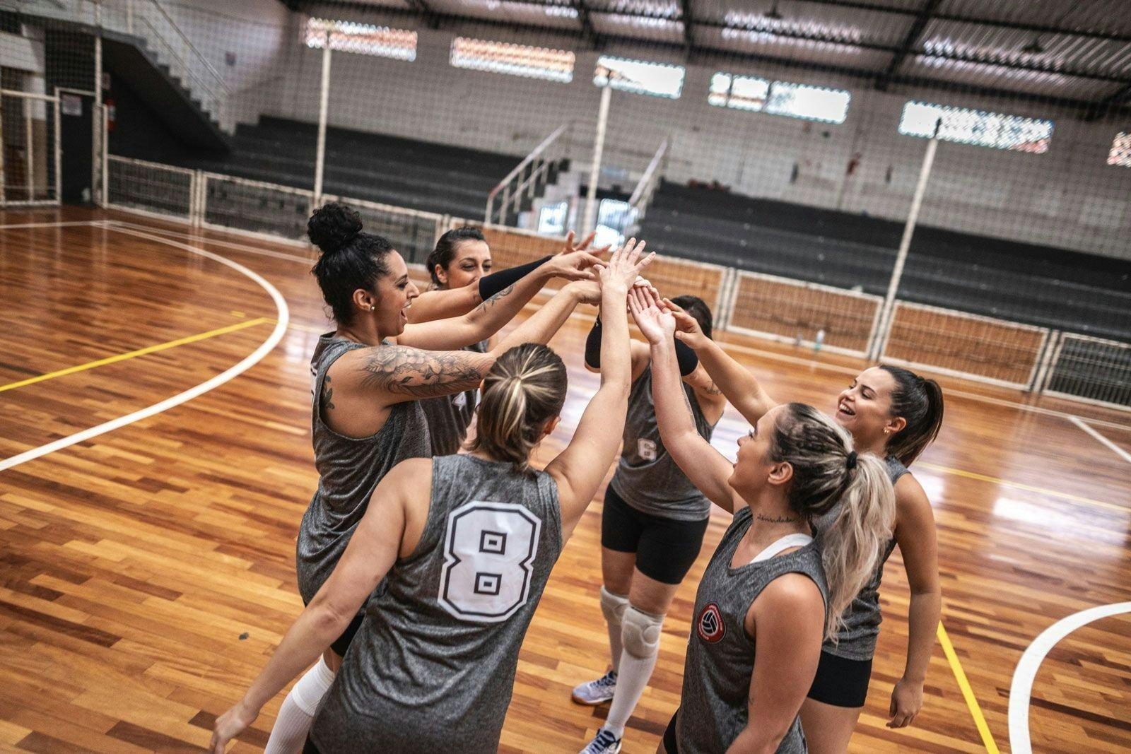 A team of volleyball players touching hands before a game