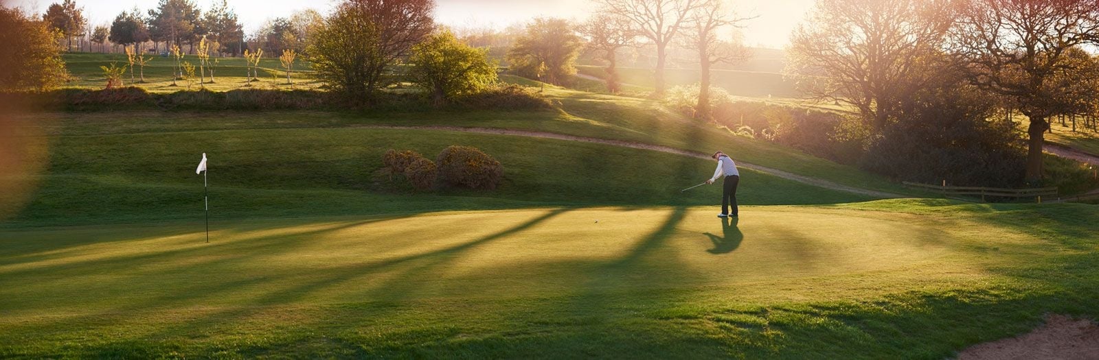 Panoramic shot of golfer playing on a sunlit course