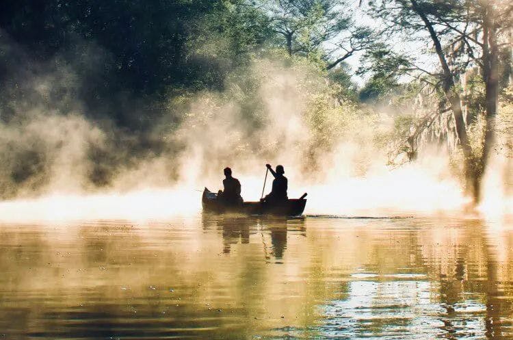 Two people in a kayak drifting through mist in Sarasota