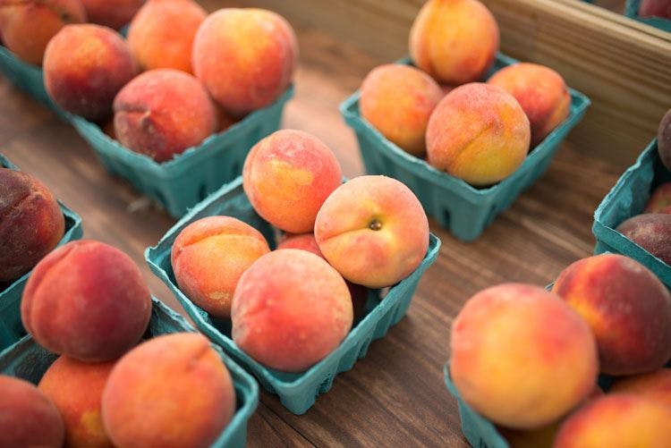 Punnetts of fresh peaches on a wooden table