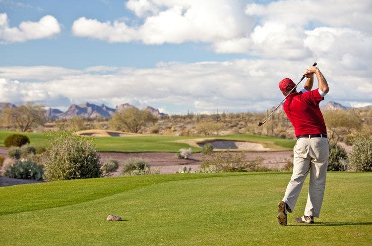 A man in red short and hat playing golf