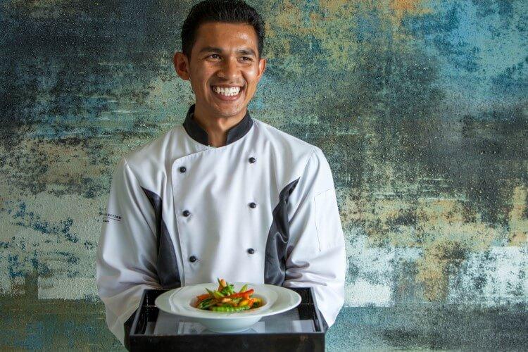 A chef holding a prepared plate of food