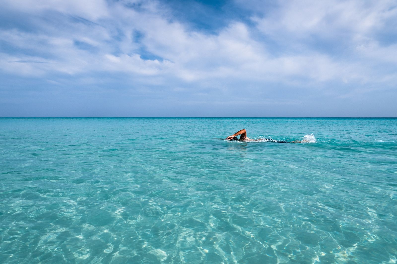 A person swimming through sparkling Caribbean Sea