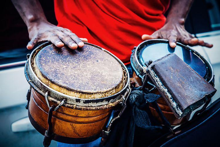A man playing lap drums and a cowbell