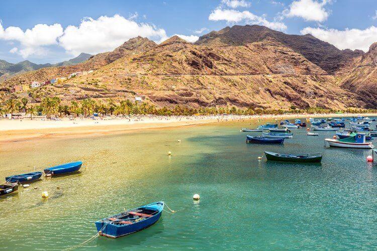 A white sand beach in Tenerife with small boats moored offshore