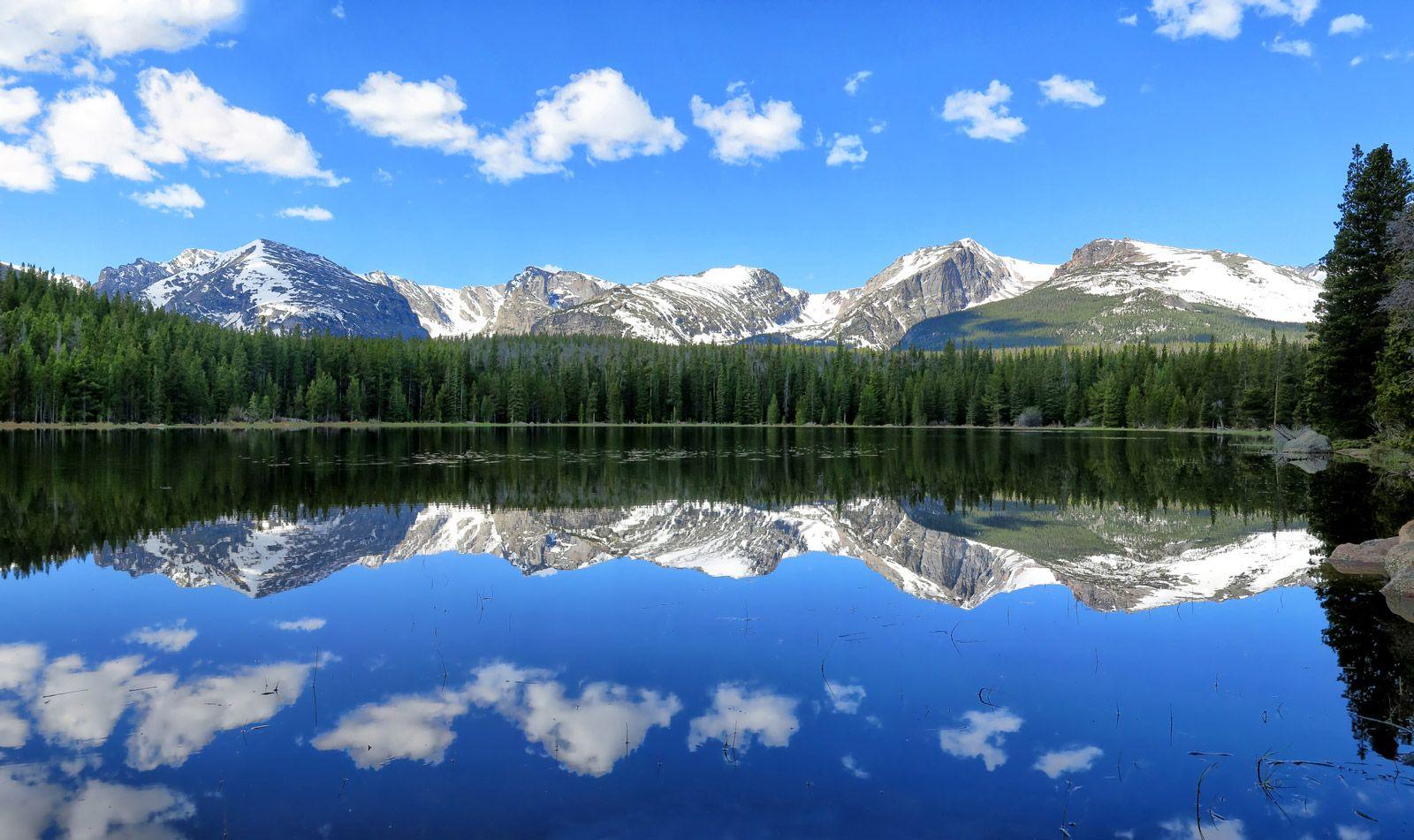 Colorado mountain landscape with a still lake reflecting the forest and mountains