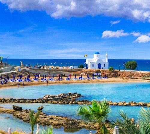 Cyprus white church with blue domed roof on a rock pier by the sea