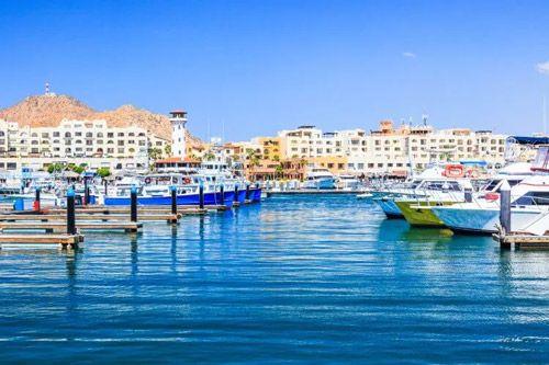 Cabo San Lucas harbor with yachts and fishing boats and buildings along the seafront