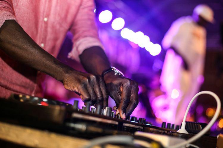 A man turning dials on a music system by a stage