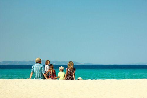 A family sitting on a white sand beach