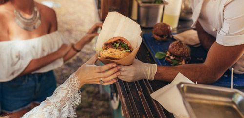 A woman being handed a burger from a street food vendor