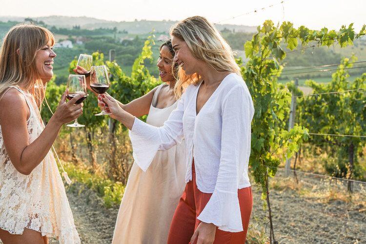 A group of female friends enjoy wine tasting in a vineyard