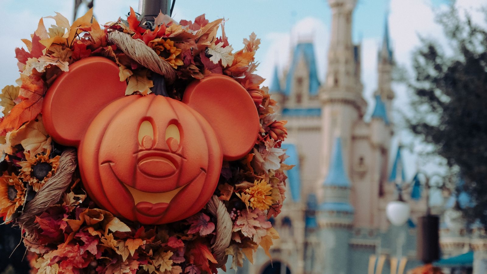 A pumpkin carved in the likeness of Mickey Mouse in front of Cinderella's Castle in Disney World