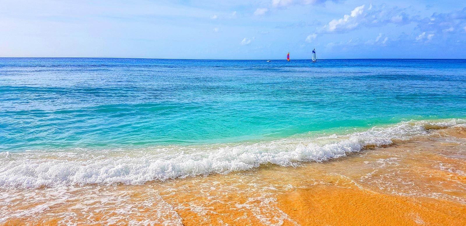 White sand beach with sailboats in the sea in Paynes Bay