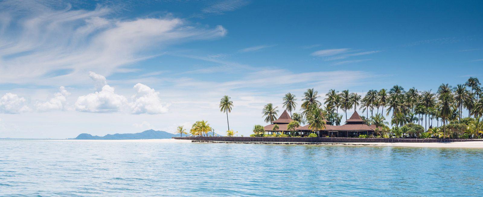 Phuket palm-fringed beach with traditional wooden buildings along the water's edge