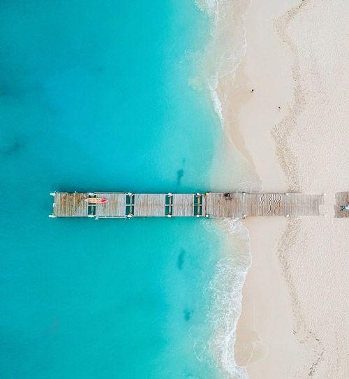 Ariel shot of wooden pier on white sand beach