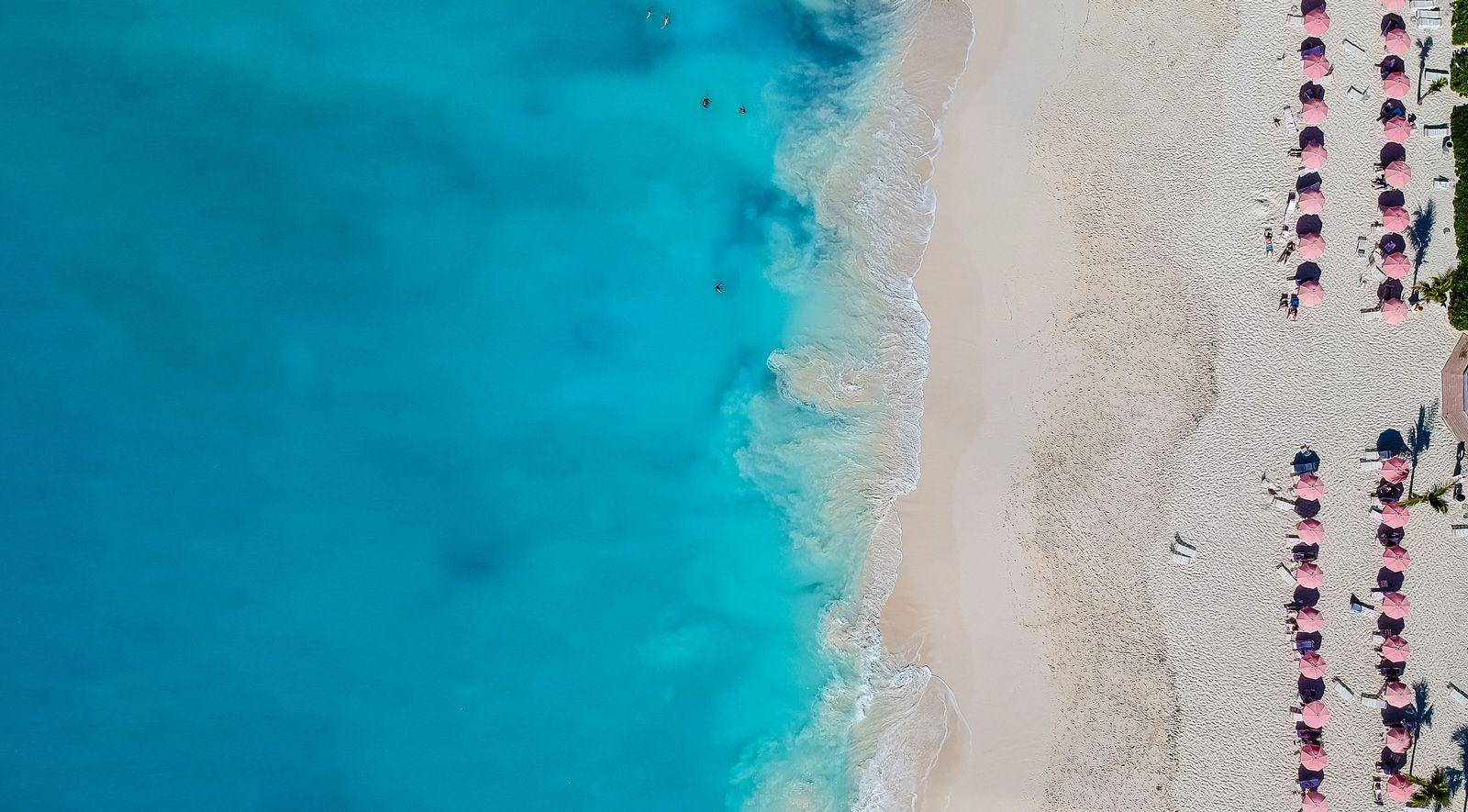 Ariel view of whit sand beach with red parasols