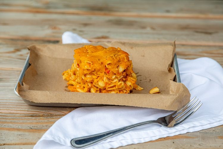 Macaroni pie in brown papers on a metal tray