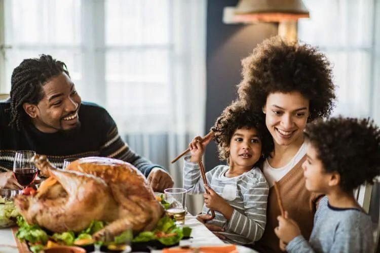 A family sit around a table laid with Thanksgiving food