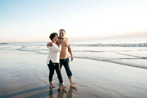 A couple walking through the surf on a beach