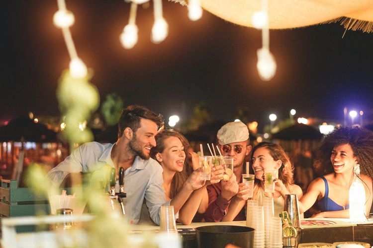 A group of friend sitting at an outdoor bar at nighttime