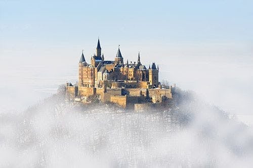 A German castle on top of a hill shrouded in fog