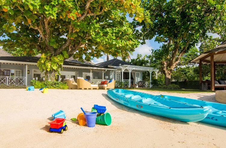 Kayaks, buckets, and beach toys on white sand
