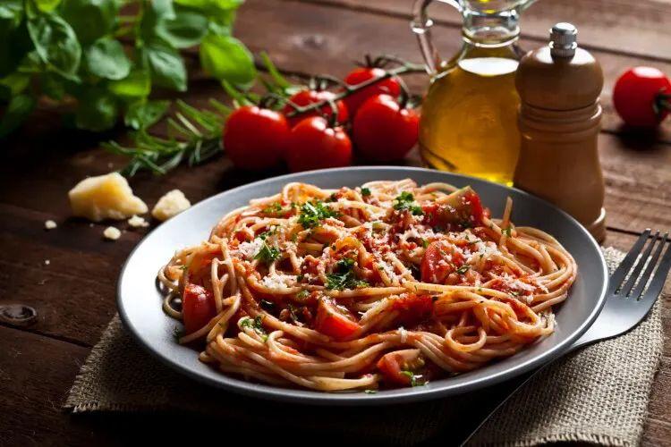 A plate of spaghetti with tomato sauce and herbs