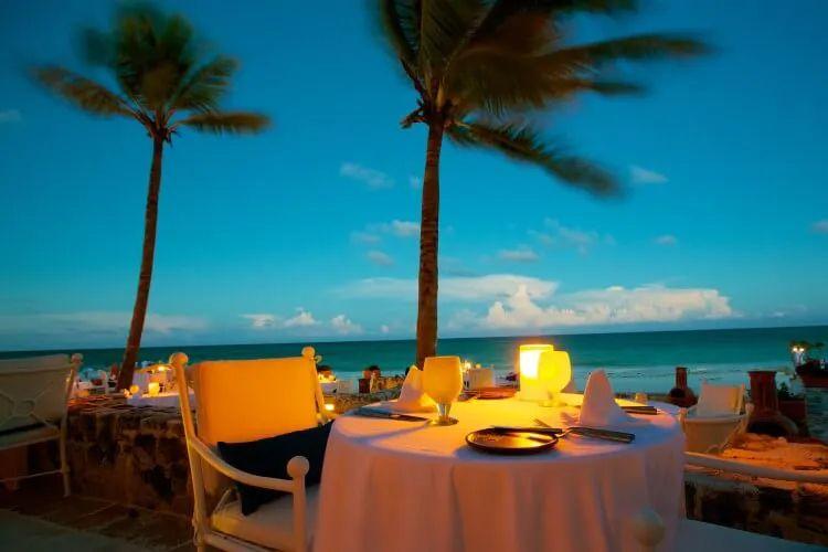 Candlelit restaurant on a beach under palm trees