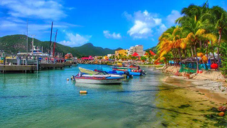 Beach at Grand Case with small fishing boats by white sand and palm trees