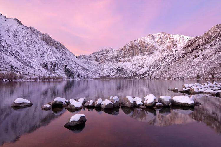 Snow-dusted mountains by a still lake in Mammoth Lakes