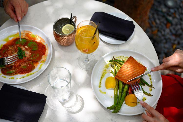 Overhead view of couple dining in restaurant on salmon and pasta
