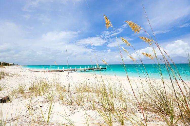 White sand beach with pier leading into turquoise water