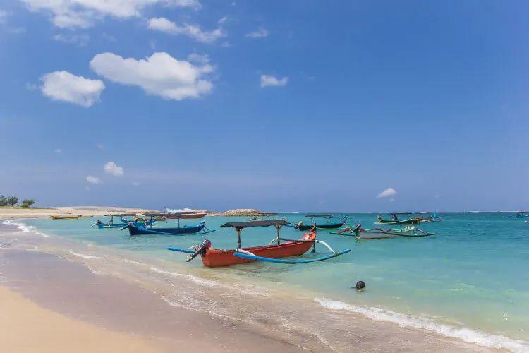 Long tail fishing boats moored on a white sand beach