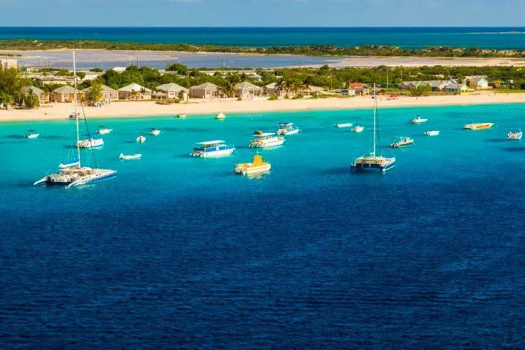 Boats moored off of a white sand beach