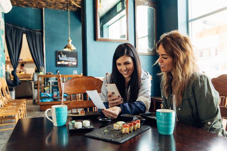 Two women sitting in a restaurant eating sushi