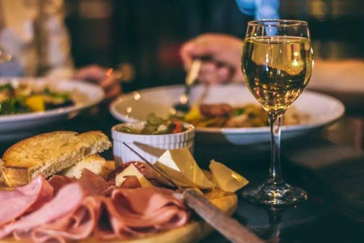 Restaurant table with wine and a plate of cold meat, cheese and bread