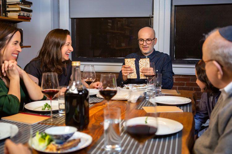A Jewish family sitting around a table breaking bread