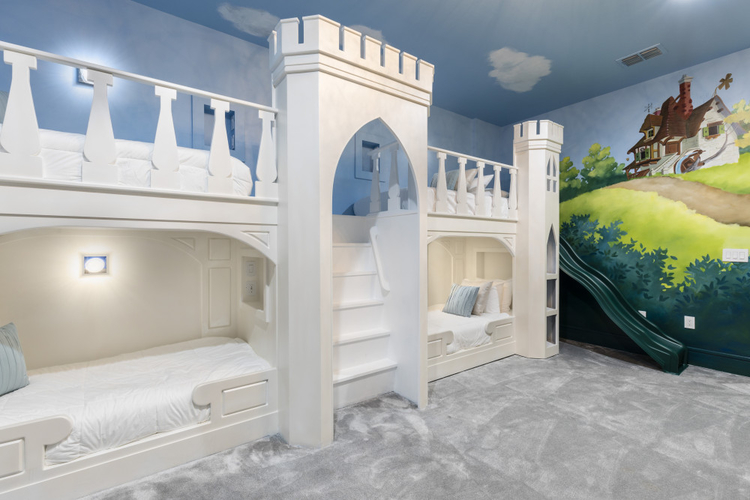 White custom-built castle bunkbed with slide and countryside mural