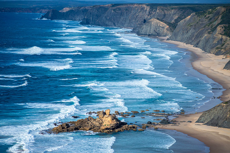 Rolling waves breaking on a beach in the Algarve - Best places to visit in January