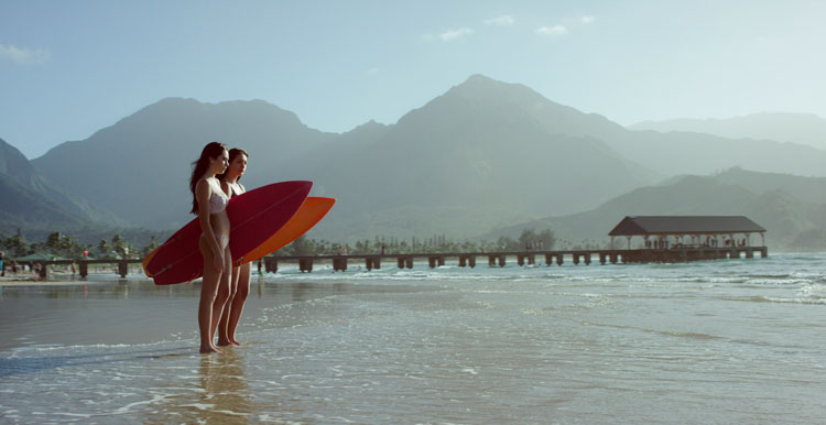 People standing in shallow water with surf boards in Hawaii - Best places to visit in January