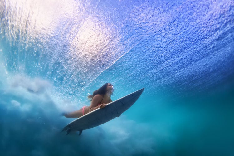 Shot from beneath the water of a eprson riding a surfboard in Maui - The best places to visit in June