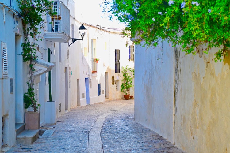 The best places to visit in September - narrow alleyway with white buildings in Ibiza